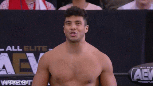 Wrestler Holding Belt In Front Of Wrestlemania Sign GIF