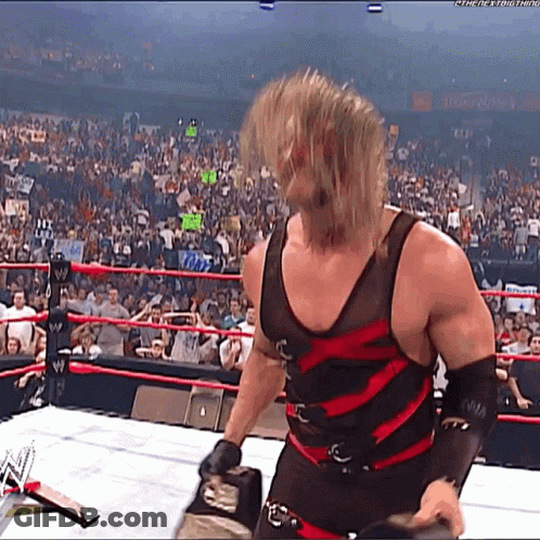 Wrestler In Black And Red Outfit In Ring With Crowd GIF