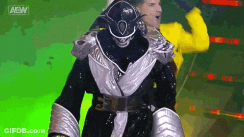 Wrestler In Black And Silver Walking With Yellow Jacket Man GIF