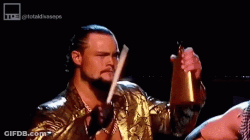Wrestler In Gold Jacket Holding Bell And Sword GIF