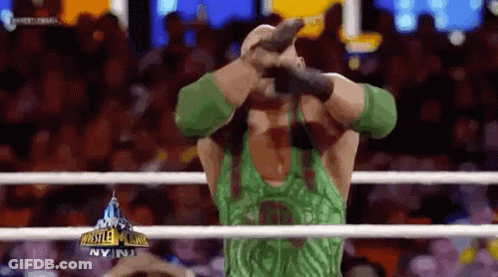 Wrestler In Green Tank Top Holding Microphone In Ring GIF