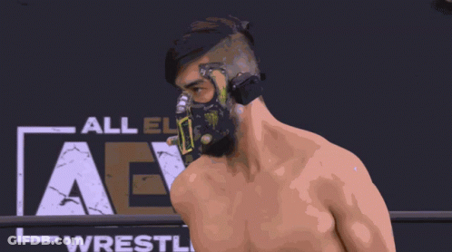 Wrestler In Mask In Front Of All Elite Wrestling Sign GIF