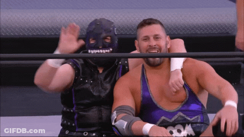 Wrestler In Mask Sitting Next To Purple Tank Top GIF