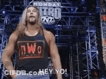 Wrestler In NWO Tank Top Standing In Front Of Stage GIF