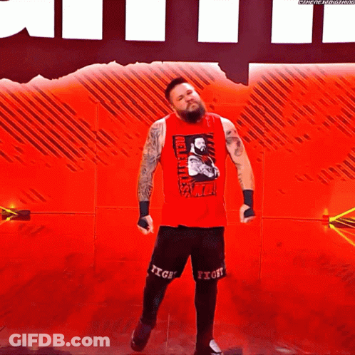 Wrestler In Red Tank Top And Black Shorts On Red Stage GIF