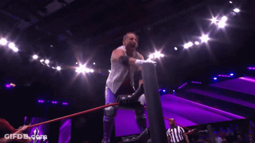 Wrestler In White Vest And Purple Shorts Arms Outstretched GIF