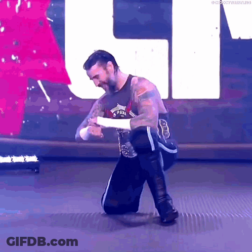 Wrestler Kneeling In Front Of Large White Letter U GIF