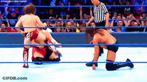 Wrestler Kneeling In Ring And Opponent Standing GIF
