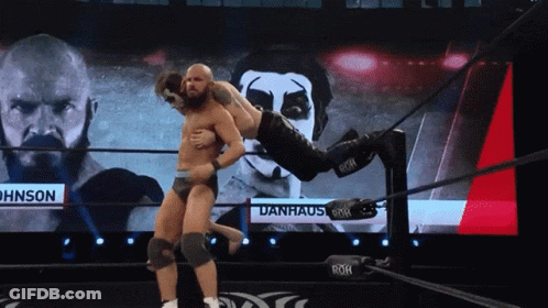 Wrestler Lifted By Another Wrestler In Front Of Danhaus Screen GIF