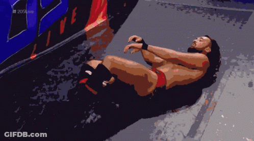 Wrestler Lying On Floor In Front Of 205 Live Wall GIF