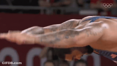 Wrestler Stretching Arms In Front Of Olympic Logo GIF