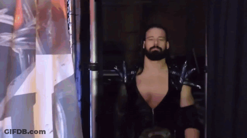 Wrestler With Beard Walking Through Doorway In Dark Room GIF