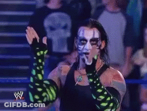 Wrestler With Green Gloves And Skull Shirt In Front Of Crowd GIF