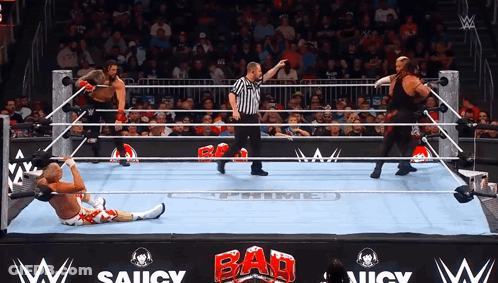 Wrestlers In A Wrestling Ring With A Sign That Says Saucy On It GIF