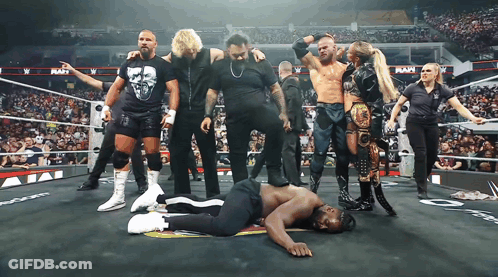 Wrestlers Standing Around Wrestler Laying On Ground GIF