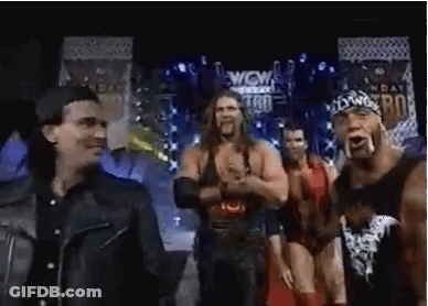 Wrestlers Standing On Stage In Front Of Wow Sign GIF