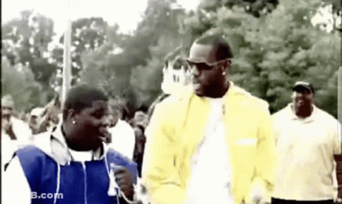 Yellow Jacket Man Talking To Blue Jacket Man In Crowd GIF