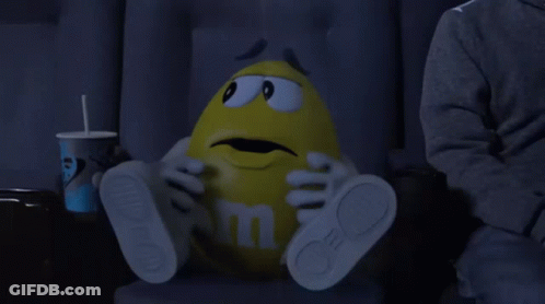 Yellow M&M Sitting In Movie Theater GIF