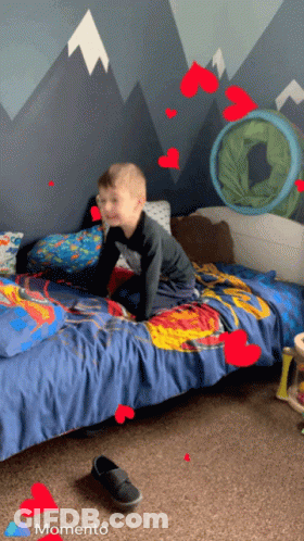 Young Boy Crawling On Bed With Hearts And Momento GIF