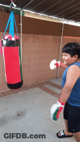 Young Boy Hitting Red Punching Bag With Boxing Gloves GIF