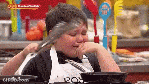 Young Boy In Apron Holding Tongs Over Mouth While Cooking GIF