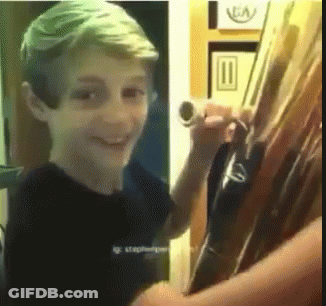 Young Boy In Black Shirt Smiling Holding Tube GIF
