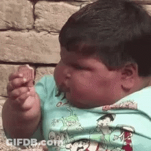 Young Boy In Blue Cartoon Shirt Eating Food GIF