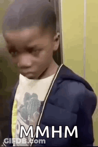 Young Boy In Blue Jacket And White Shirt In Front Of Yellow Wall GIF