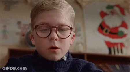Young Boy In Glasses And Blue Sweater Beside Santa Claus Decoration GIF