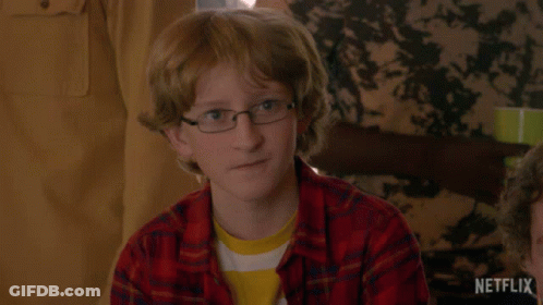 Young Boy In Glasses And Plaid Shirt Sitting At Table GIF