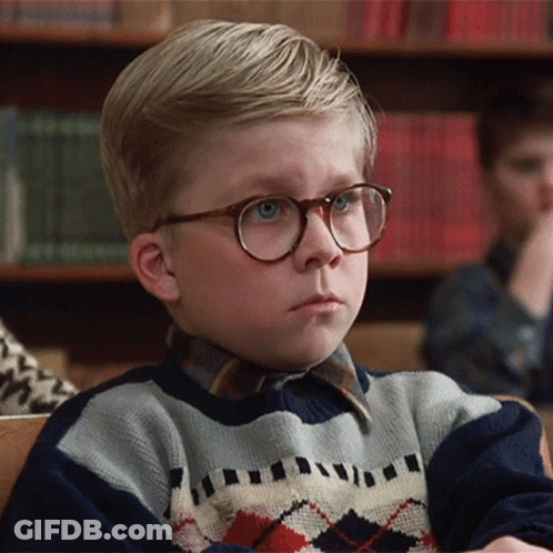 Young Boy In Glasses And Plaid Sweater Sitting In Classroom GIF
