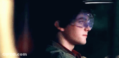 Young Boy In Goggles Smiling In Dark Room GIF
