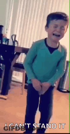 Young Boy In Green Sweater Standing With Hands In Pockets GIF