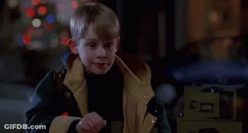 Young Boy In Jacket In Front Of Christmas Tree In Dark Room GIF