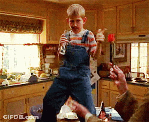 Young Boy In Overalls Standing On Table Holding Glass GIF