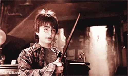Young Boy In Plaid Shirt Holding Wand In Dark Room GIF
