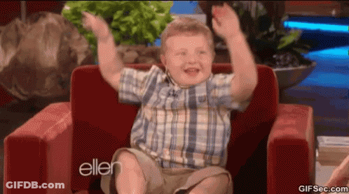 Young Boy In Plaid Shirt Sitting In Red Chair With Arms Up GIF