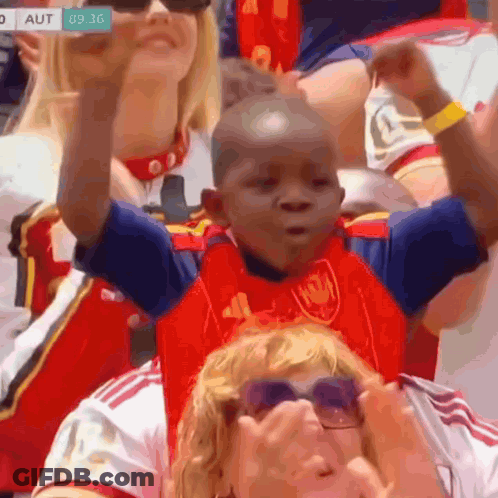 Young Boy In Red And Blue Adidas Shirt Sitting In Crowd GIF
