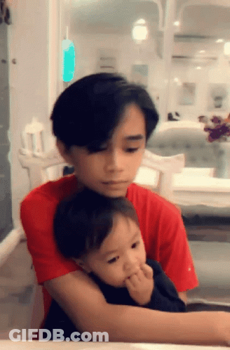 Young Boy In Red Shirt Holding Baby GIF
