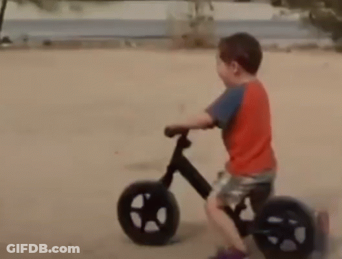 Young Boy In Red Shirt Riding Bike On Dirt Road GIF
