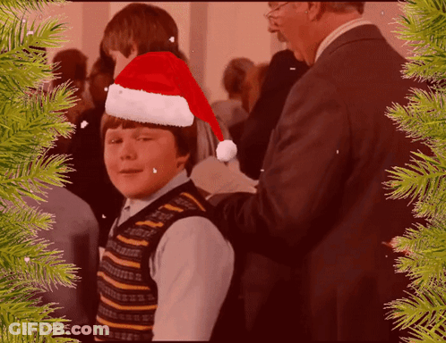 Young Boy In Santa Hat Helped By Man In Suit GIF