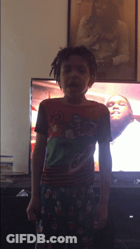Young Boy In Superhero Shirt In Front Of TV GIF