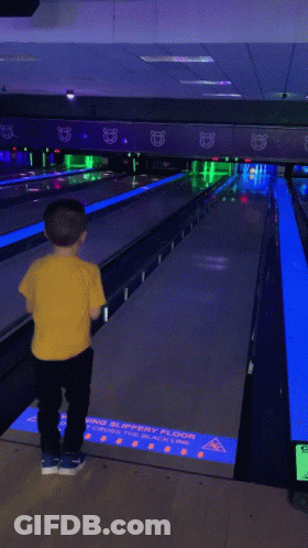 Young Boy In Yellow Shirt With Truck Playing Bowling GIF
