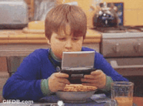 Young Boy Playing Video Game With Cereal And Orange Juice GIF