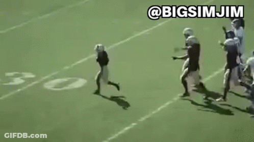 Young Boy Running On Football Field With Players GIF