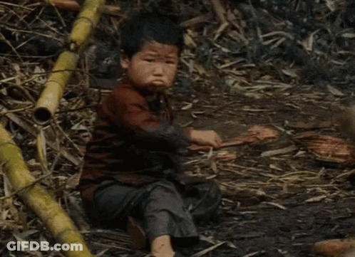 Young Boy Sitting In Dirt Holding Saw GIF