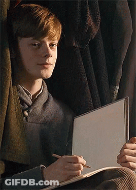 Young Boy Sitting In Front Of Window Holding Notebook And Pencil GIF