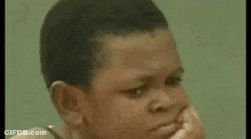Young Boy Sitting On Rock At Beach Looking At Camera GIF