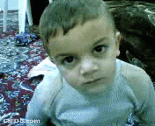 Young Boy Sitting On Rug Looking At Camera GIF