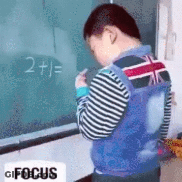 Young Boy Standing In Front Of Blackboard With 2 Plus 1 GIF